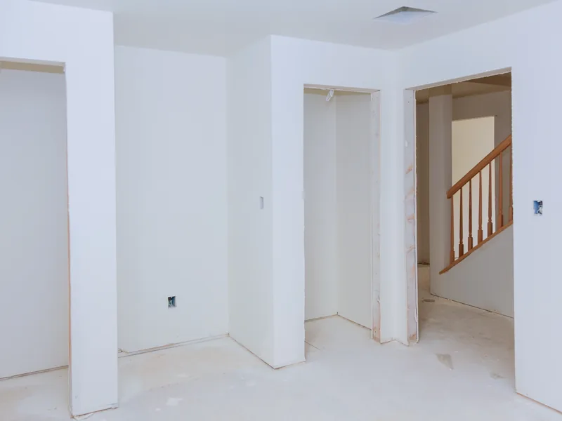 A boarded room opening onto a stair with a closet framed into one wall