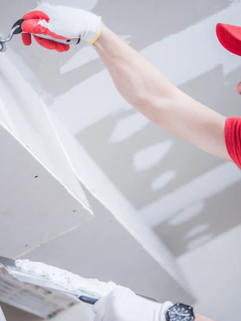 A worker bedding tape into the underside of a boxed-in ceiling drop