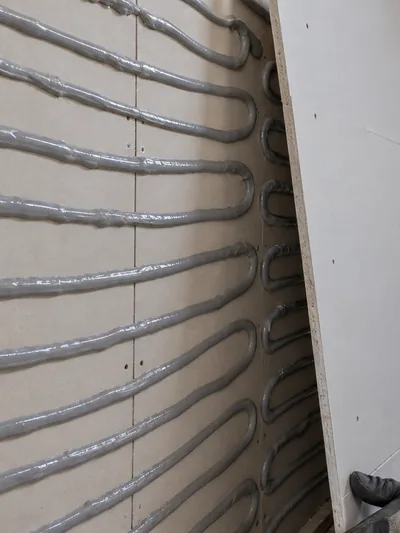 Damping compound laid in serpentine beads across a panel before the second layer