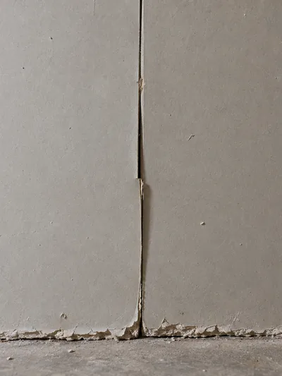 A butt joint left open between two panels with screws driven through the paper