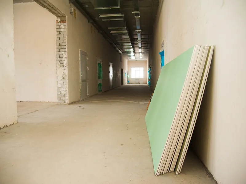 A bare corridor with a green panel leaning against the wall