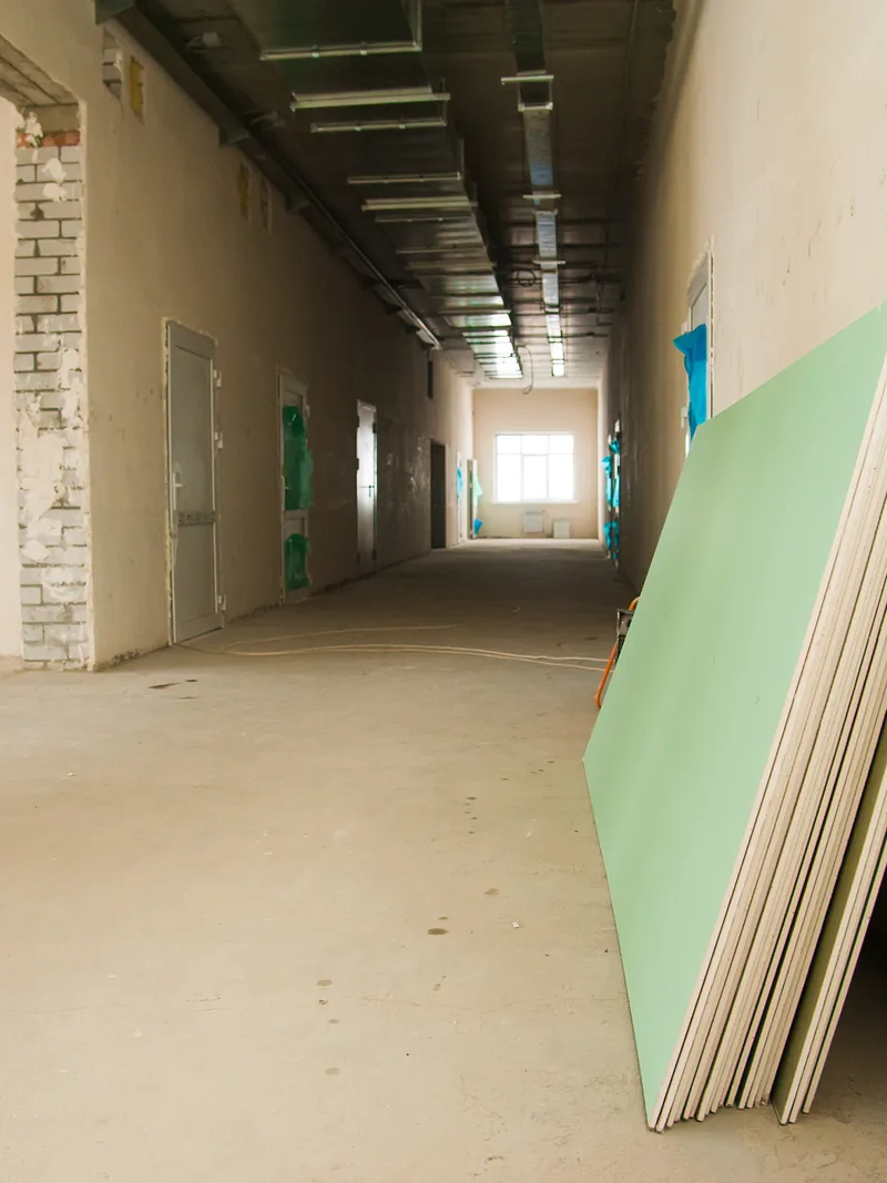 A bare corridor with a green panel leaning against the wall