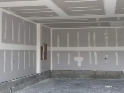 A wide boarded commercial room with the ceiling and walls all taped out