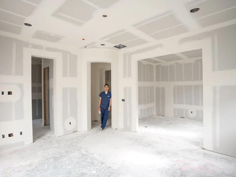 A long boarded room with a single figure standing at the far end