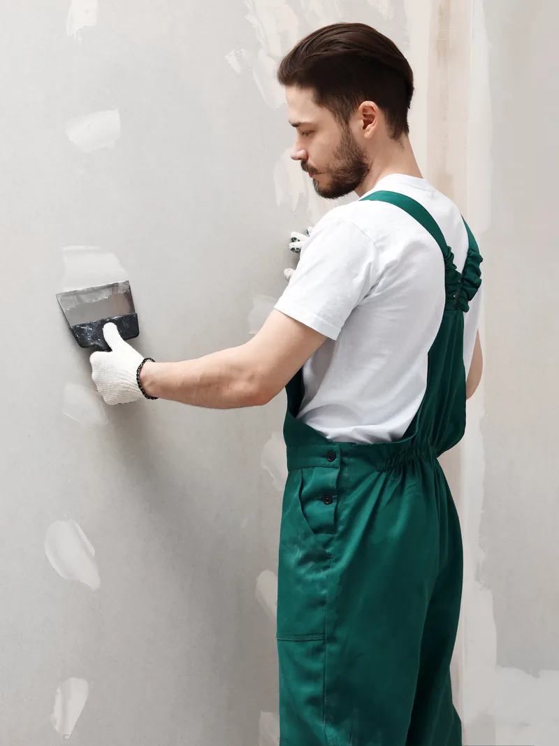 A worker working compound into a wall with a small knife
