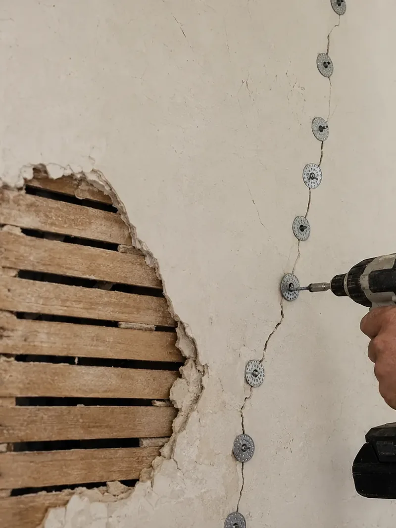 Plaster washers drawing a cracked plaster wall back to its wood lath