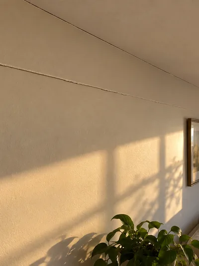 A straight crack opening along a taped seam above a furnished room
