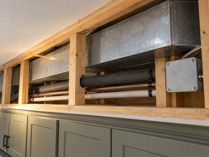 An opened soffit showing the duct, pipework and junction box running inside it