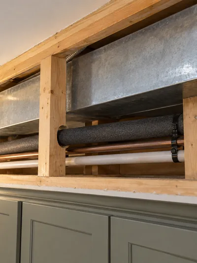 An opened soffit showing the duct, pipework and junction box running inside it