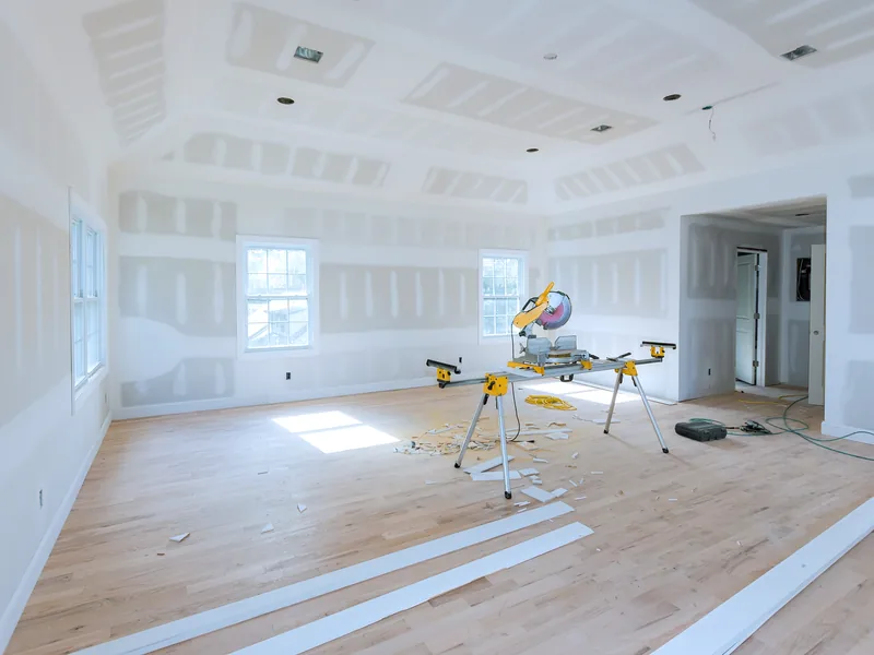 A large boarded room with a coffered ceiling and a mitre saw set up in it