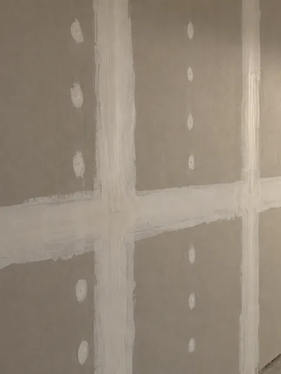 A wall with its joints taped and every screw head spotted with compound