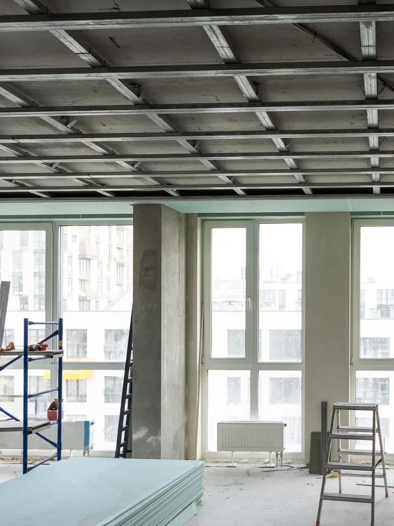 A commercial room with an open suspended ceiling grid and a scaffold tower