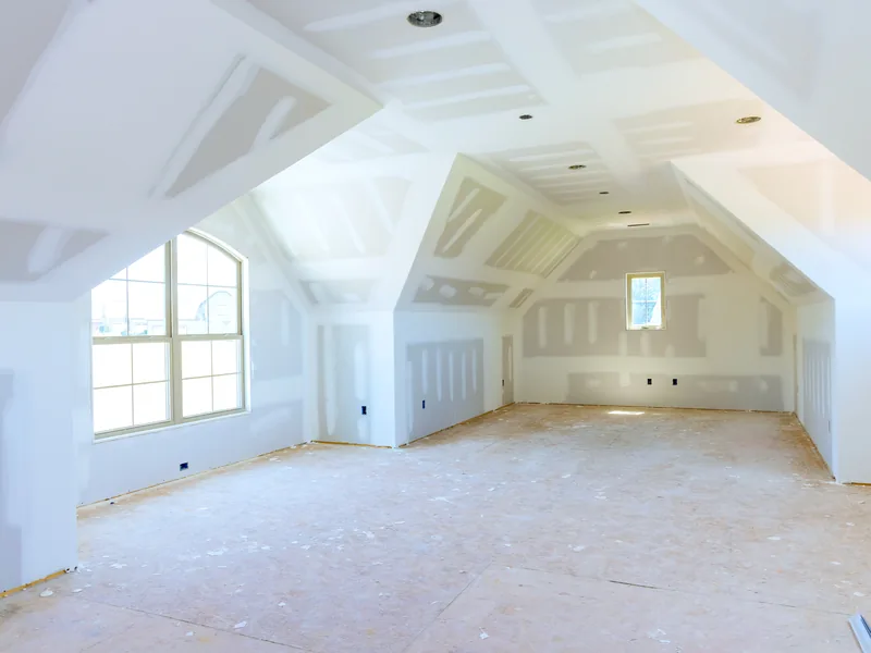 A boarded attic room with sloping ceilings and new windows