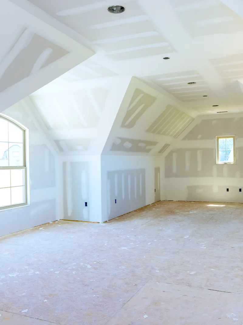 A boarded attic room with sloping ceilings and new windows